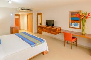 Schlafzimmer mit einem Bett, einem Schreibtisch und einem TV in der Unterkunft Hotel Loma Real in Tapachula