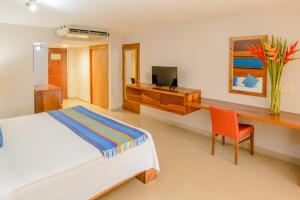 a bedroom with a bed and a desk and a television at Hotel Loma Real in Tapachula