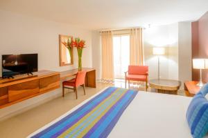 Hotel Loma Real في تاباتشولا: غرفة في الفندق بسرير وتلفزيون وغرفة
