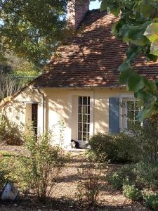 un gato sentado en la puerta de una casa blanca en La Chaine, en Saint-Jean-du-Bois