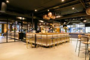 a restaurant with a bar with gold stools at Hotel Marktstad in Schagen