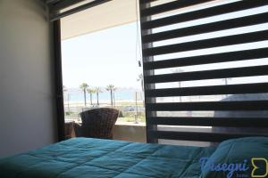 1 Schlafzimmer mit einem Fenster mit Blick auf den Strand in der Unterkunft Departamento Av del Mar Coquimbo Disegni 03 in Coquimbo