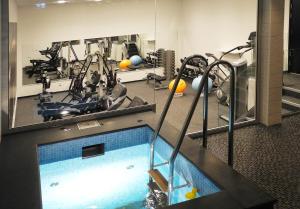 a gym with a swimming pool and exercise equipment at Clarion Collection Hotel Slottsparken in Linköping