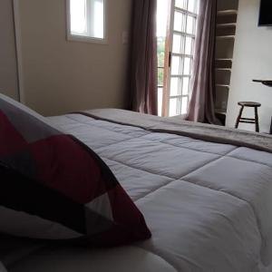 een groot bed in een slaapkamer met een raam bij Suítes Campos do Jordao bairro Capivari in Campos do Jordão