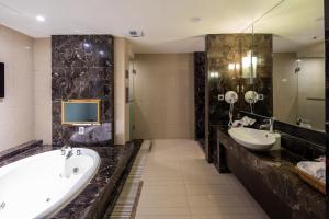 a bathroom with two sinks and a tub and a television at Discovery Motel - Nangang in Taipei