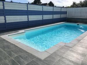 a swimming pool with blue water in front of a fence at Villa Garance Ile et Villas Groix in Groix
