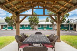 a patio with a table and chairs under a pergola at CASTLE Waimea Country Lodge in Waimea