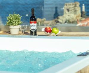 a bottle of wine and apples on a table next to a swimming pool at Castel Abaso Boutique Apartments by Explore Andros in Andros