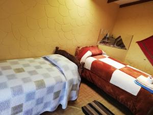 two beds in a room with yellow walls at Hostal Palacio del Inca in Comunidad Yumani