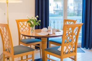 a wooden table with chairs and a vase of flowers at Hotel Aquamarin in Kühlungsborn