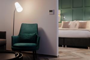a green chair in a room with a bed at The Embassy Valletta Hotel in Valletta