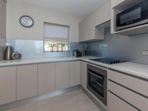 Shoalhaven 4 28 Voyager Cl - waterfront unit with stunning views and Wifi في خليج نيلسون: مطبخ مع دواليب بيضاء وساعة على الحائط