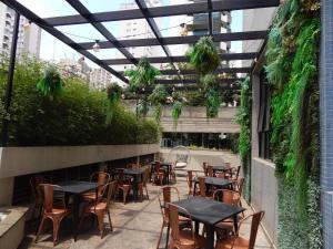 un patio al aire libre con mesas, sillas y plantas en Mercure Sao Paulo Moema, en São Paulo