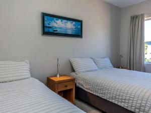 Shoalhaven 4 28 Voyager Cl - waterfront unit with stunning views and Wifi في خليج نيلسون: غرفة نوم بسريرين وتلفزيون على الحائط