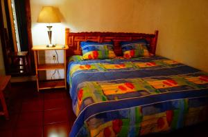 Hospedaje La Hoja في تيبوزتلان: غرفة نوم مع سرير مع لحاف ملون