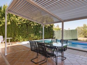 a patio with a glass table and chairs and a pool at Belvilla by OYO Casa de Rudi in Seville
