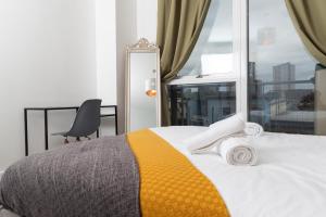 a bedroom with a bed and a chair and a window at Stylish Birmingham City Centre Apartment in Birmingham