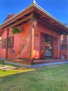 una casa roja con una hamaca fuera de ella en Luz da Lua Cabanas Comfort, en Praia do Rosa