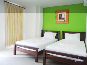 two beds in a room with a green wall at Ivory Phi Phi Island in Phi Phi Don