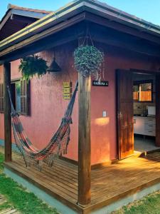 a porch with a hammock outside of a house at Luz da Lua Cabanas Comfort in Praia do Rosa