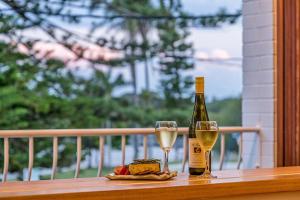 a bottle of wine and two glasses on a balcony at The Terrace Penthouse Apartment in Brunswick Heads