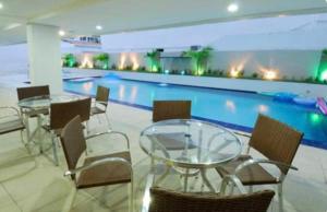 een zwembad met tafels en stoelen in een gebouw bij Imperial Flat in João Pessoa