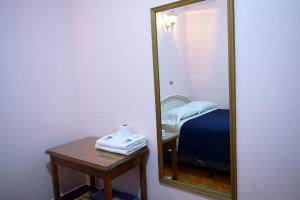 espejo en una habitación con cama y mesa en Hotel Posada del Centro en Guatemala