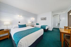 a hotel room with two beds and a desk at Stagecoach Motel Wodonga in Wodonga