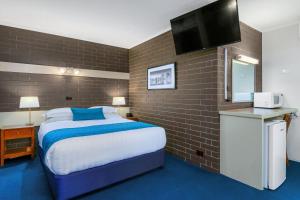 a hotel room with a bed and a flat screen tv at Stagecoach Motel Wodonga in Wodonga