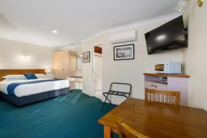 a hotel room with a bed and a table at Stagecoach Motel Wodonga in Wodonga