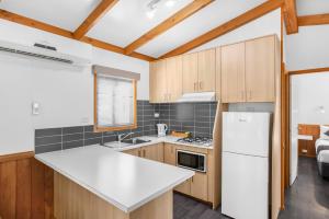 a kitchen with wooden cabinets and a white refrigerator at Breeze Holiday Parks - Halls Gap in Halls Gap