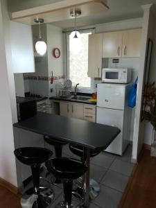 a kitchen with a black table and two bar stools at DEPARTAMENTO FRENTE A LA PLAYA 3 personas in Valparaíso