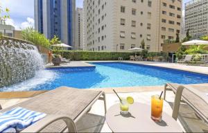 a swimming pool with a table and a drink at Flat na Paulista no Hotel Transamerica Particular in Sao Paulo
