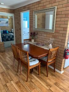 a dining room table with chairs and a mirror at Beachlander Self-Contained Holiday Apartments in Coffs Harbour