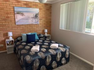 a bedroom with a bed and a brick wall at Beachlander Self-Contained Holiday Apartments in Coffs Harbour