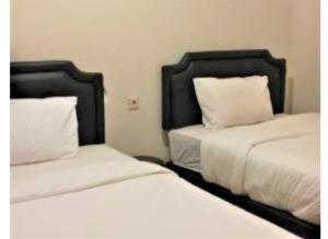 2 camas en una habitación con sábanas y almohadas blancas en Siwalankerto F7, en Surabaya