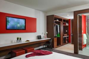 a bedroom with a red accent wall and a tv on the wall at Mere Hotel in Winnipeg