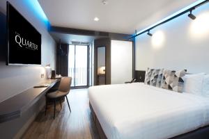 a hotel room with a bed and a desk and a television at The Quarter Silom by UHG in Bangkok