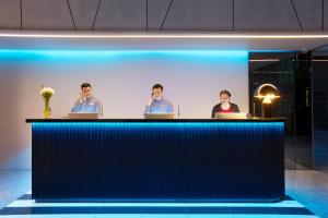 a group of three people sitting at a bar in a room at The Quarter Silom by UHG in Bangkok