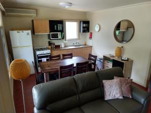 a living room and kitchen with a couch and a table at Cockatoo Cabin in Halls Gap
