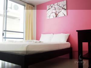 Bett in einem Zimmer mit einer rosa Wand in der Unterkunft Ivory Phi Phi Island in Ko Phi Phi