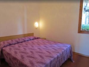 ein Schlafzimmer mit einem lila Bett und einem Fenster in der Unterkunft Bright flat in a poolside residence - Beahost in Bibione
