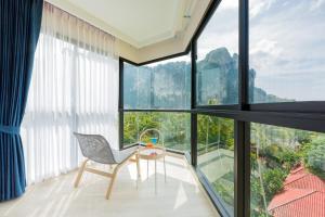 um quarto com uma cadeira, uma mesa e janelas grandes em Vacay Aonang Hotel em Praia de Aonang