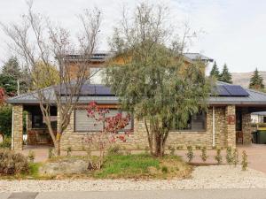 a brick house with a tree in front of it at Aspiring Apartment Wanaka in Wanaka