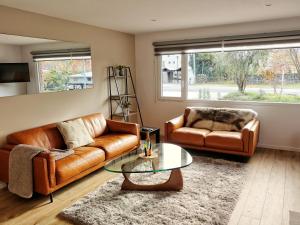 a living room with two leather couches and a glass table at Aspiring Apartment Wanaka in Wanaka