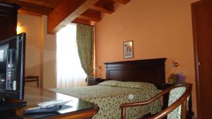 a bedroom with a bed and a desk with a television at Hotel Archimede Ortigia in Syracuse