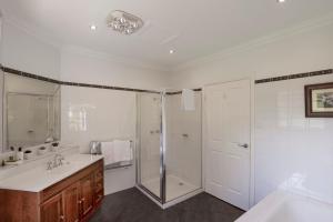 a white bathroom with a shower and a sink at Toorongo River Chalets in Noojee