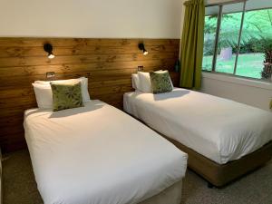 two beds in a room with wooden walls and windows at The Warby, where mid-century style meets the mountains in Warburton