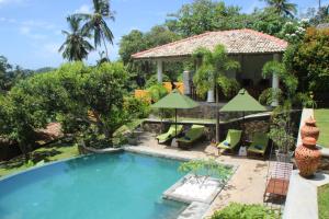 a pool with chairs and umbrellas next to a house at The Spice House Mirissa in Mirissa