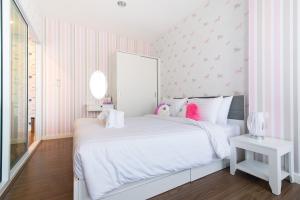 a bedroom with a white bed with pink stripes at Courtyard khaoyai by JP in Mu Si